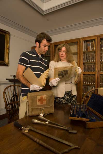 a professor and student studying historical materials and artifacts
